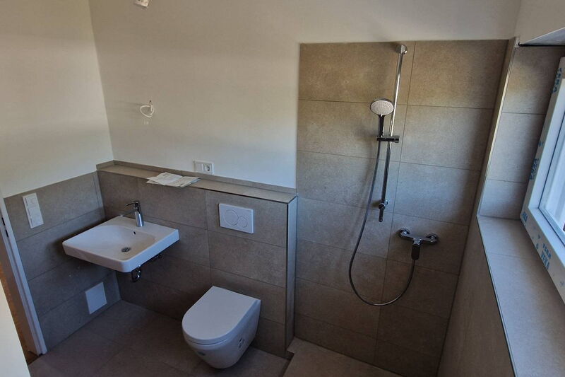 Waschtisch, Wand-WC mit gefliester Ablage und Dusche am Fenster, halbhohe Wandfliesen