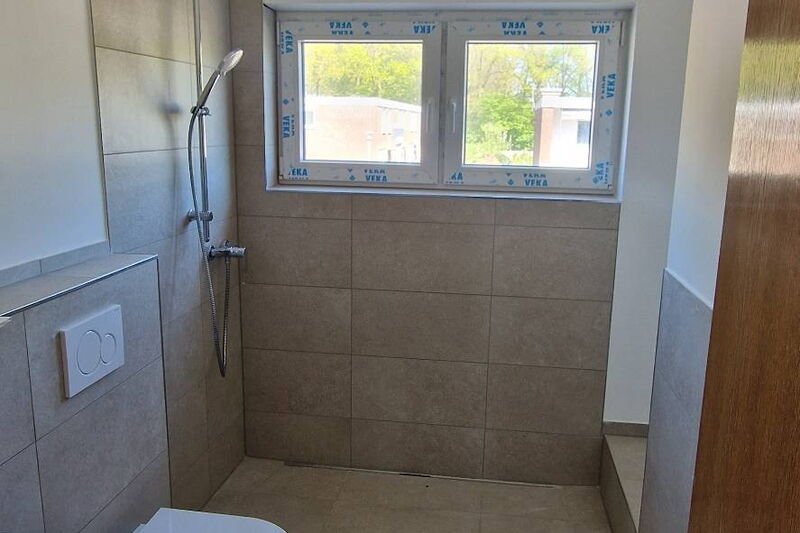 Nachher: Dusche mit Podest und Handbrause, großformatige Fliesen in Sandtönen, Wand-WC