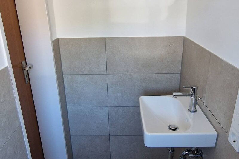 Nachher: kleines Handwaschbecken im Gäste-WC, Wand halbhoch gefliest